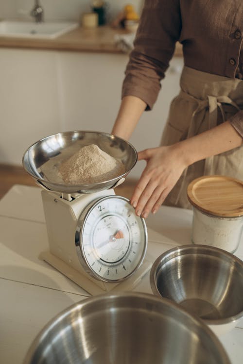 Woman Using Kitchen Scales for Weighing Flour