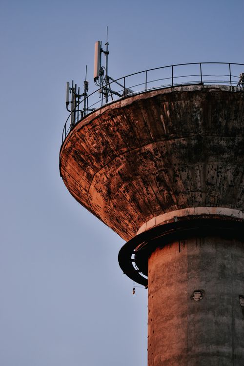 Free Old rusty water tower photographed in close-up against a clear blue sky, showcasing its aged texture. Stock Photo