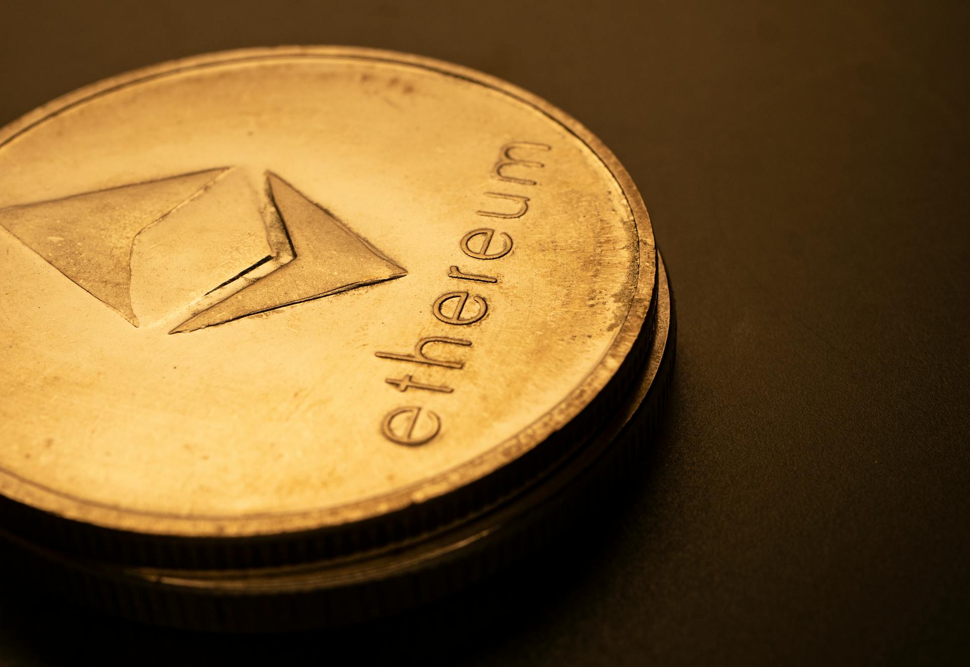 Detailed macro shot of an Ethereum logo coin against a dark background.