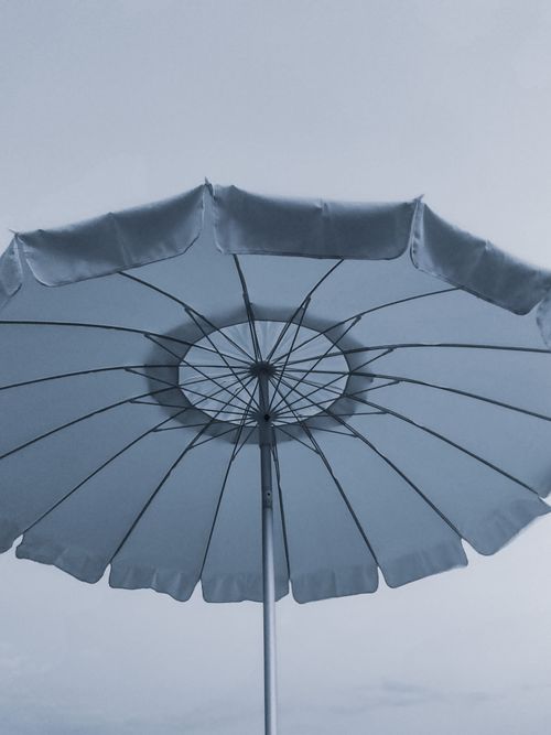 Free A low angle view of a blue sun umbrella against a clear sky, providing shade and style. Stock Photo