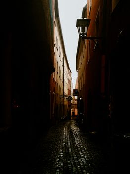 Dark, atmospheric photo of a narrow cobblestone alley between historic buildings.