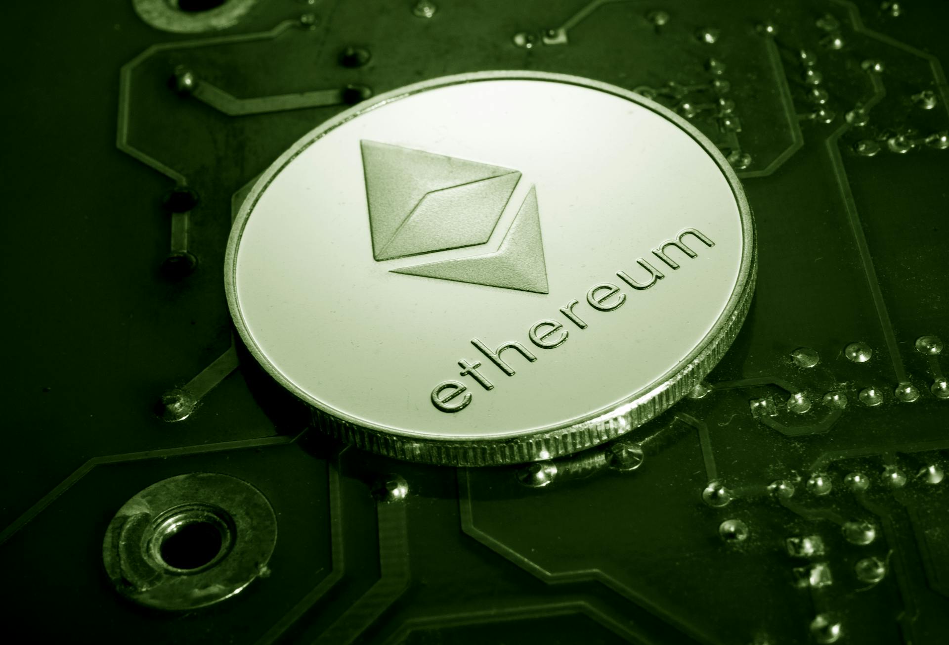 Close-up of an Ethereum coin placed on a circuit board, symbolizing digital currency technology.