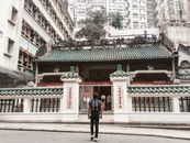 Man in Black Jacket Standing Near Red and White Concrete Building
