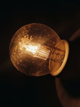 A glowing light bulb captured in darkness, showcasing intricate details and warm lighting.