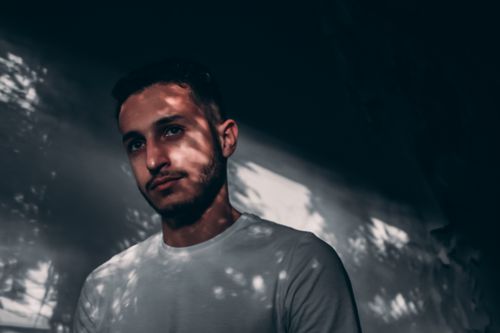 Free Moody portrait of a bearded man in shadowed light, wearing a white shirt. Stock Photo