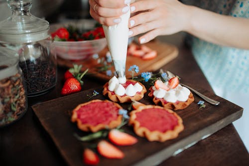 Crop woman decorating cookies with cream