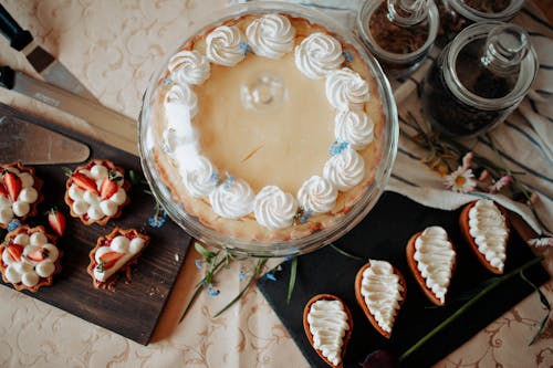 Free Top view of appetizing cake and desserts with whipped cream near knives and flowers on table Stock Photo