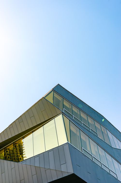 Free Low-angle view of a modern glass building against a clear blue sky. Stock Photo