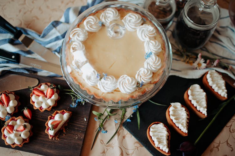 Cake Under Glass Cover Near Cupcakes