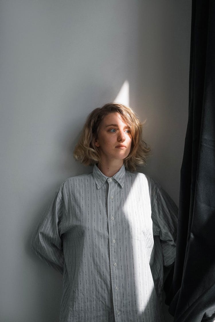 A Scared Woman Leaning On The Wall While Looking Afar