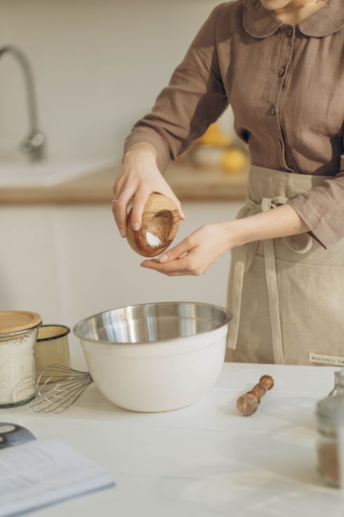 Free Close-up of a woman adding salt to a bowl in a kitchen setting. Stock Photo