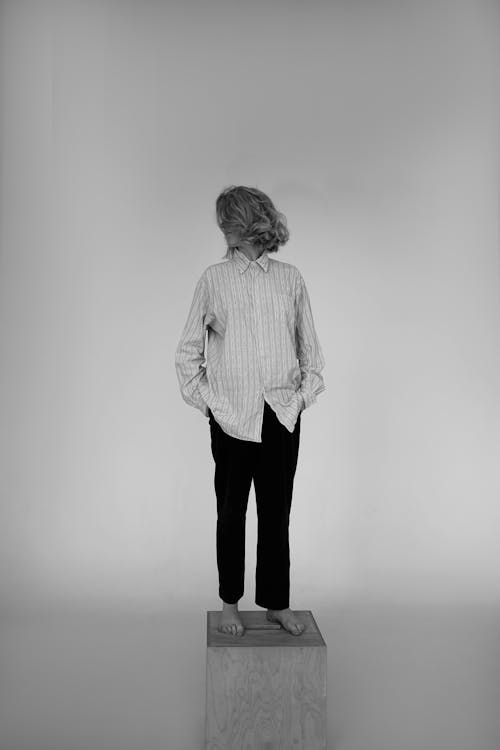 Grayscale Photo of a Person Standing on a Box