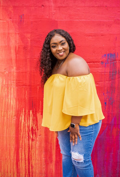 Free Woman in Yellow Off Shoulder Top and Blue Denim Jeans Stock Photo