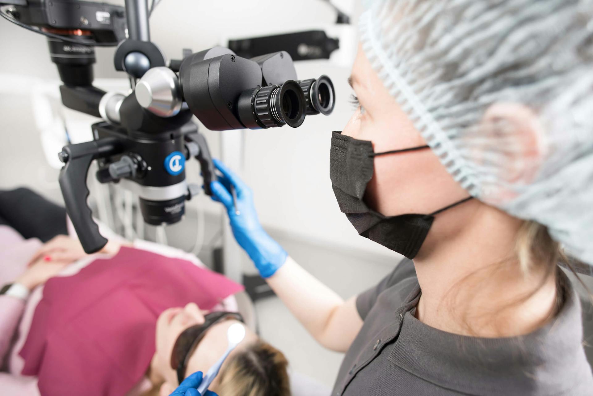 Dentist in clinic with microscope treating patient, Kyiv, Ukraine.