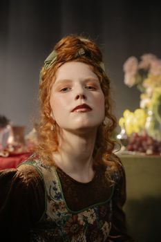 Elegant portrait of a redhead woman in vintage attire set against a blurred still life background.