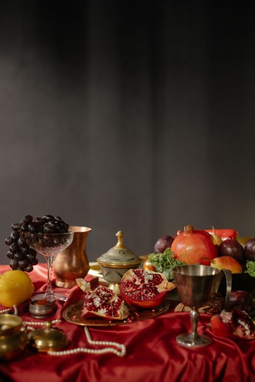 Free Opulent baroque-style still life featuring fruits and ornate tableware on rich fabric. Stock Photo
