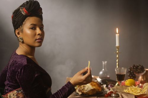 Free A woman enjoys a meal with wine and candlelight, featuring elegant fashion and decor. Stock Photo