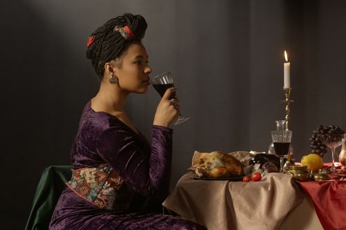 Free Woman enjoying wine in a Renaissance-themed dining setting with candles and food. Stock Photo