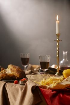 Cozy candlelit dinner setup with wine, roast chicken, and fries.
