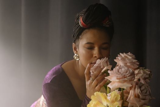 A Woman in Purple Long Sleeves Smelling Flowers with Her Eyes Closed