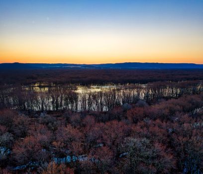 Stunning aerial shot of Trevino, WI featuring a forest and swamp under a vibrant sunset sky.