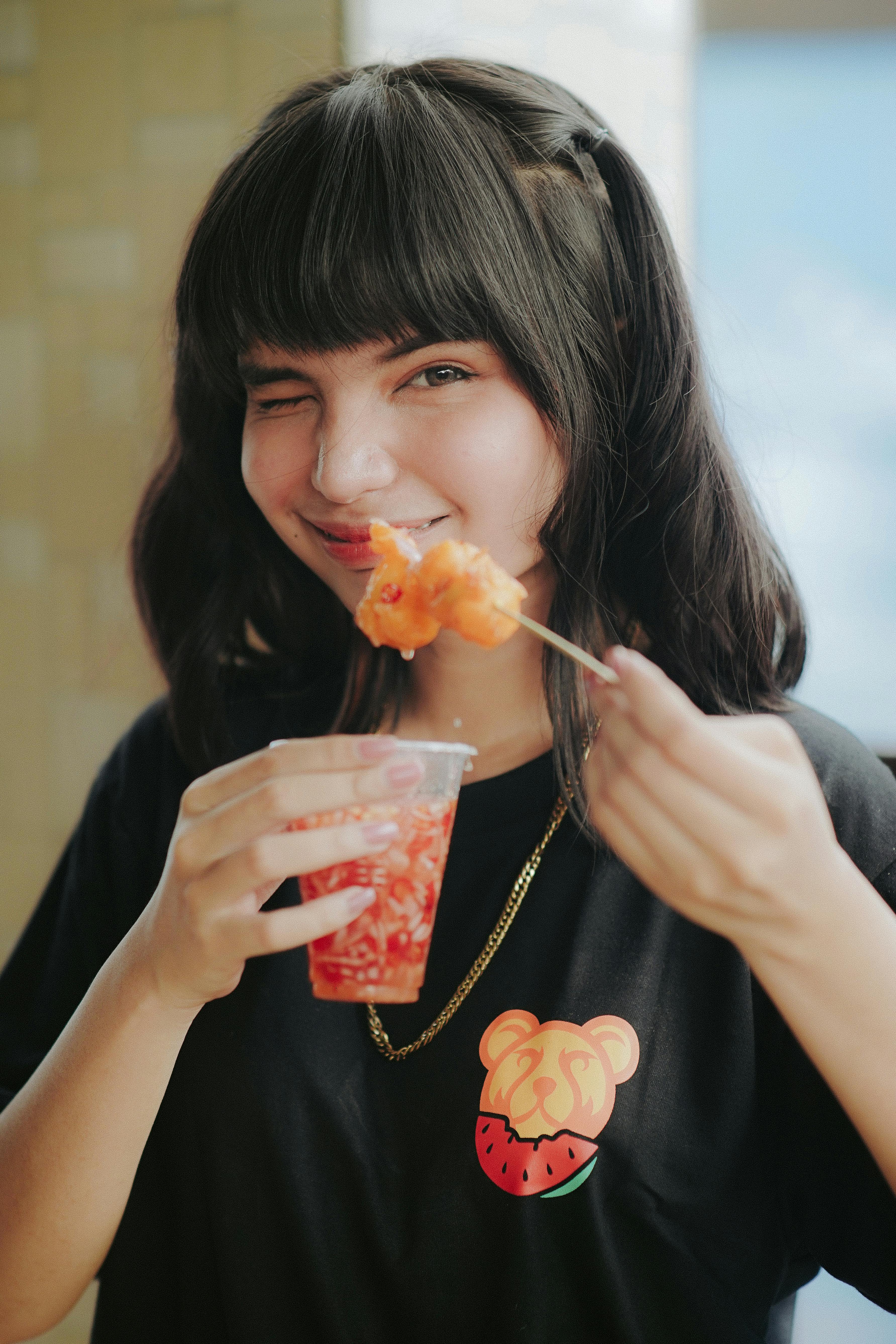 woman holding a plastic and eating street food