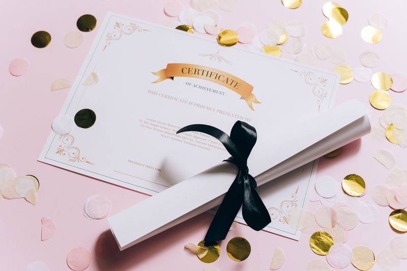 Élégant certificat de réussite sur une surface rose avec des confettis. Parfait pour les célébrations et les réalisations.