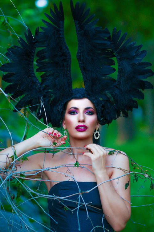 Free Model with a bold feathered headdress posing elegantly in nature Stock Photo