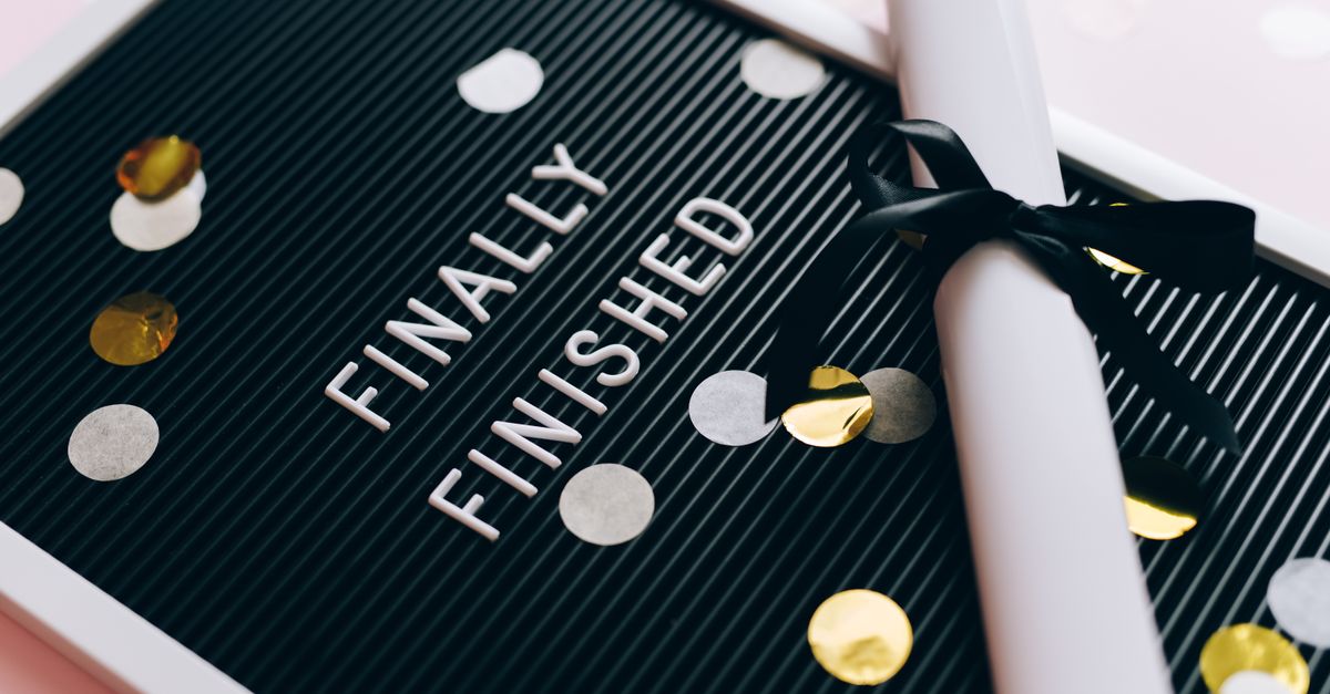 Close-up of a graduation diploma and letter board with "Finally Finished," surrounded by confetti.
