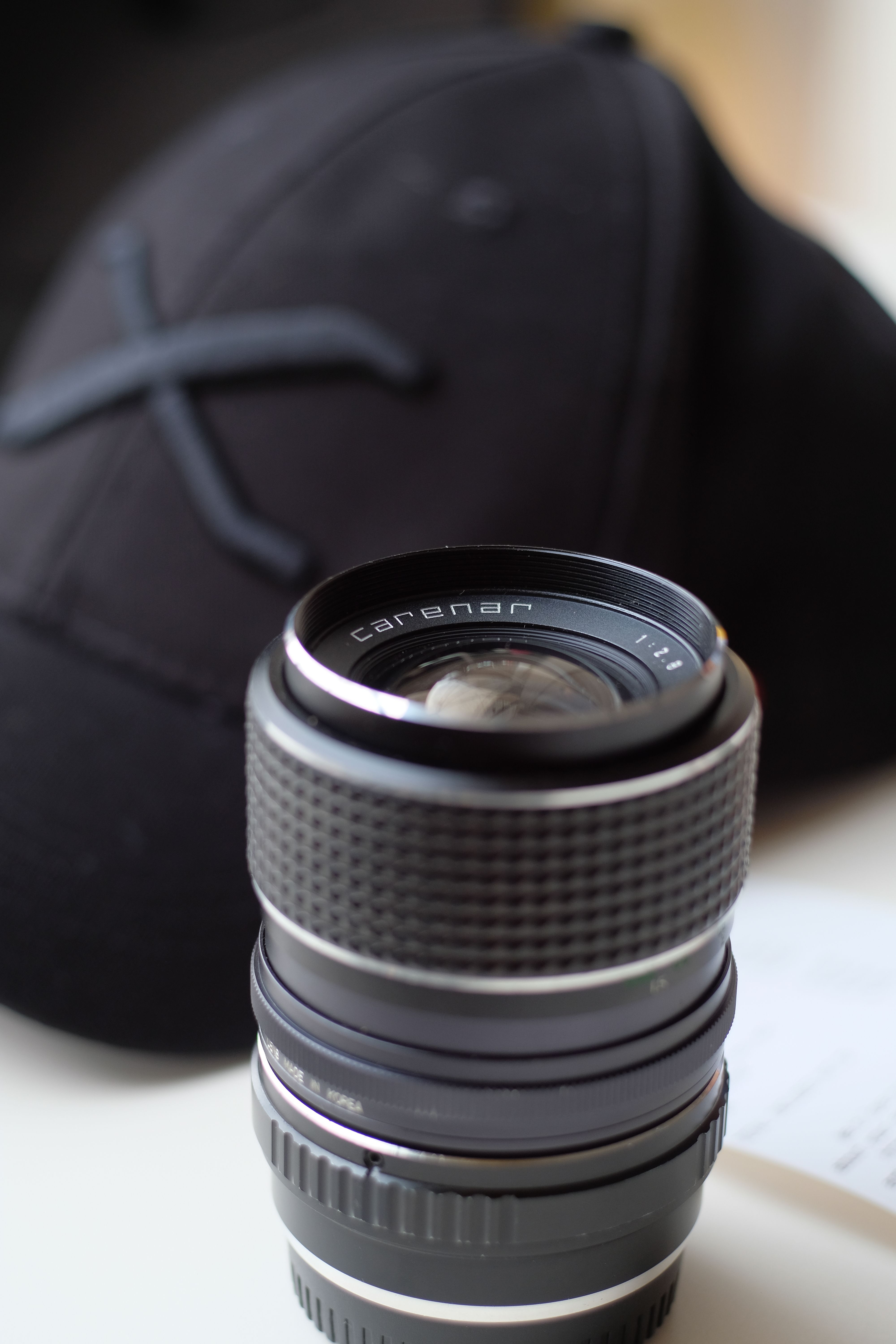 Detailed view of a camera lens beside a black cap, perfect for photography themes.