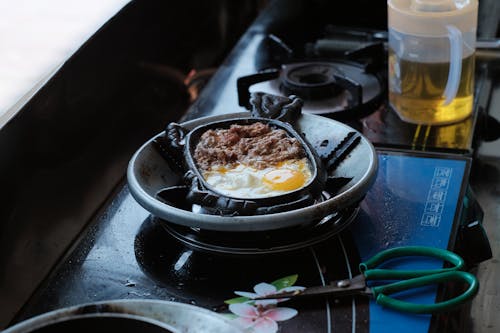 Free Egg and Meat in a Black Plate on the Stove Stock Photo