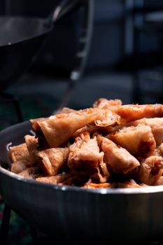 A close-up view of crispy fried spring rolls in a metallic bowl, perfect for food photography.