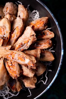 Delicious crispy spring rolls filled with vegetables, presented on a black dish.