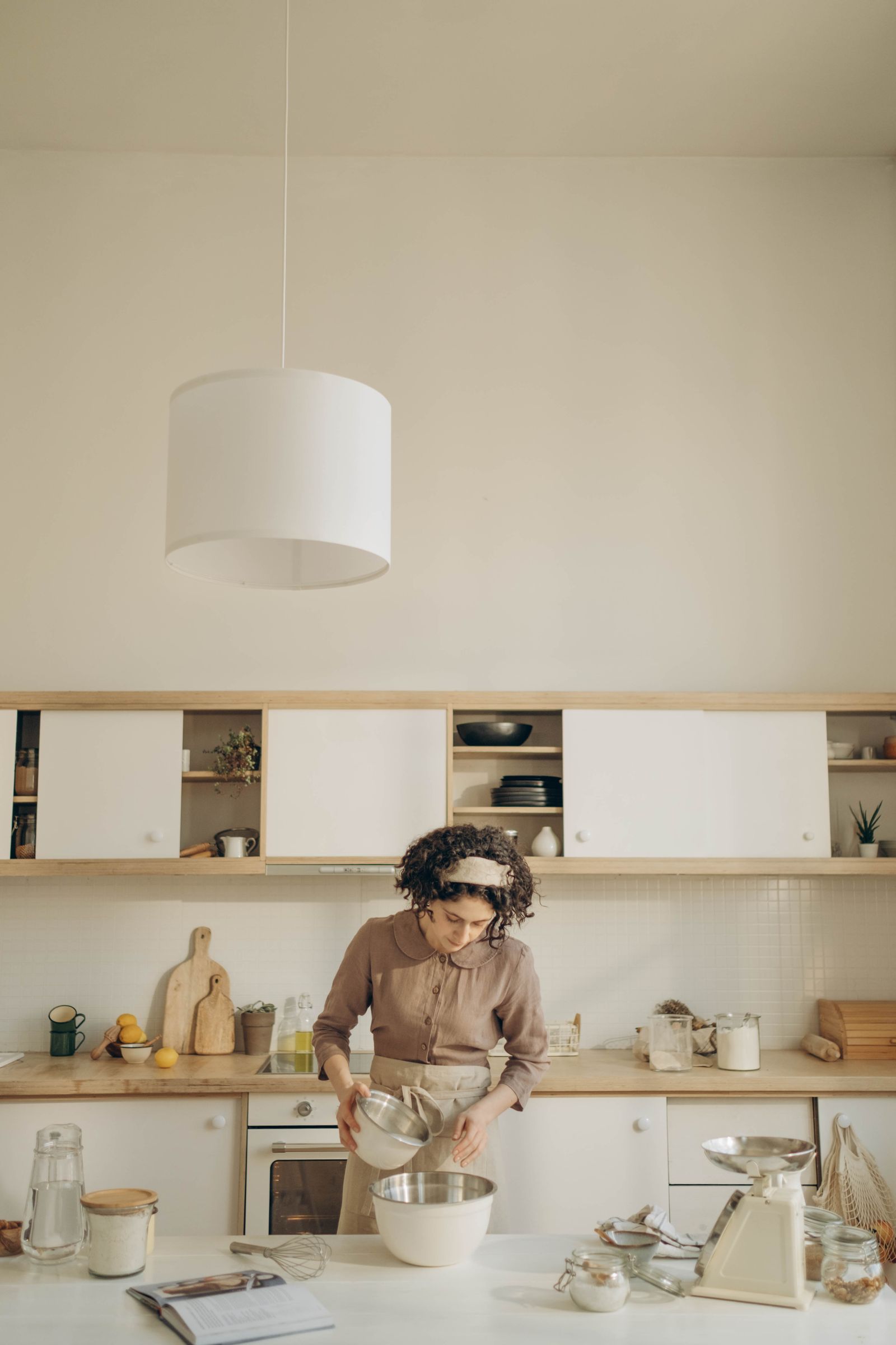 A woman prepares batter in a stylish kitchen with mixing bowls and utensils.