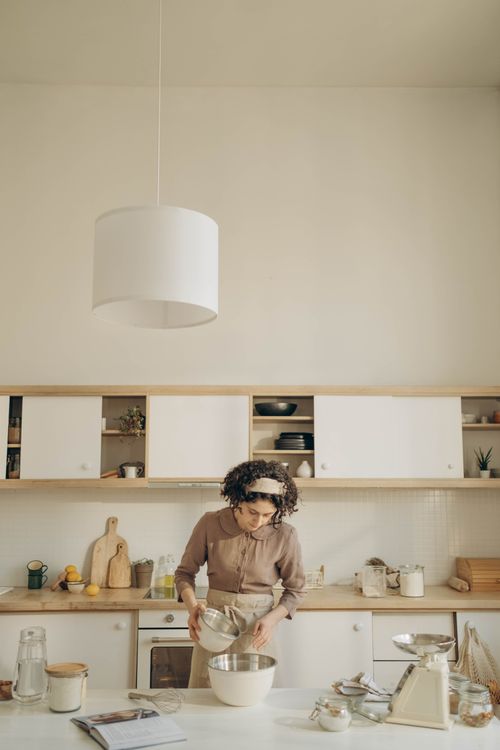 Free A woman prepares batter in a stylish kitchen with mixing bowls and utensils. Stock Photo