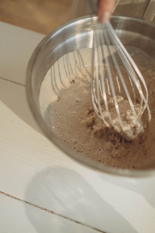 A Person Mixing Water and Flour Using a Wire Whisk