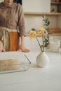 Dough in a Clear Glass Tray Beside a White Vase with Flowers