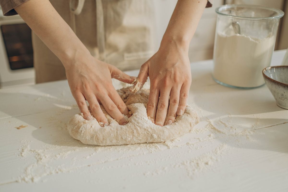 Hands kneading sourdough on a floured table. Photo by Ron Lach on Pexels