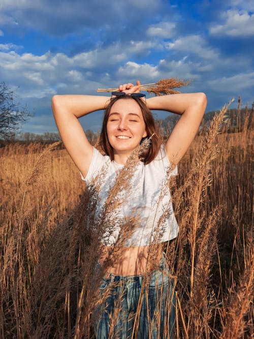 Photo of a Woman in a White Shirt Posing with Her Hands on Her Head