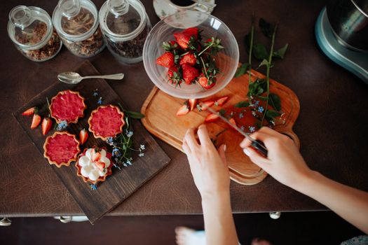 Aerial view of strawberry tart preparation with fresh fruit on cutting board.