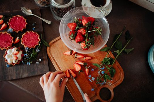 Top view of fresh strawberries being sliced on a wooden board, perfect for delicious desserts.
