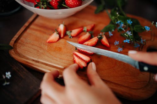 Free Selective Focus Photo of a Person's Hand Slicing Red Strawberries Stock Photo