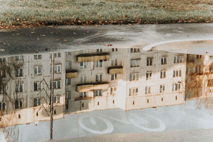 Reflection Of Concrete Building On The Puddle Of Water