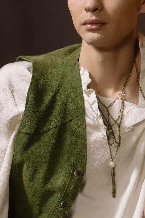 Free Detailed close-up of a fashion-forward style featuring a green vest and layered necklaces. Stock Photo