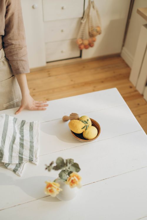 Free A warm kitchen tabletop with lemons, a striped cloth, and fresh flowers. Stock Photo
