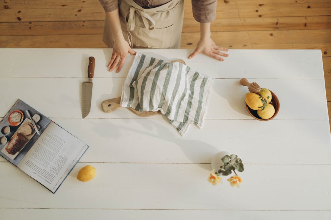 Free Person Wearing Brown Apron Standing Near the White Wooden Table  Stock Photo