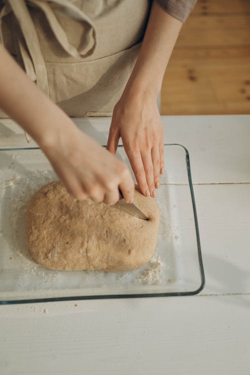 Person Holding Brown Dough on White Table