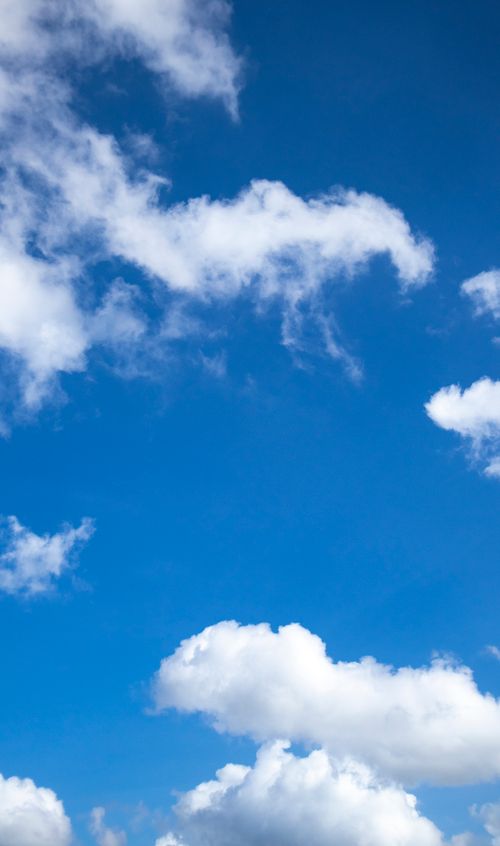 Free Bright blue sky filled with scattered fluffy clouds, ideal for nature and weather themes. Stock Photo