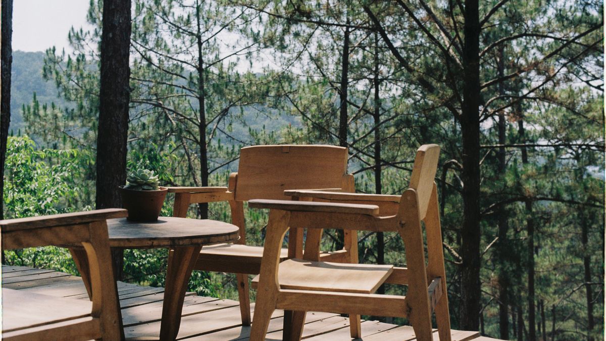 A finished wood deck with outdoor furniture overlooking trees.