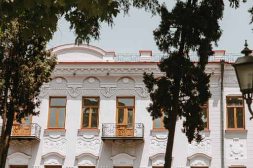 Free Charming historical building with intricate details and balconies framed by trees. Stock Photo